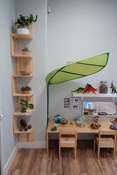 there is a green umbrella in the corner of this room with wooden tables and chairs