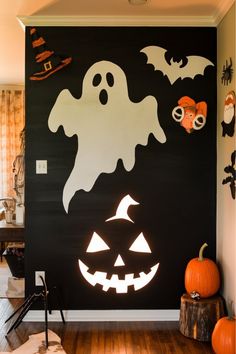 a halloween scene with pumpkins and ghost faces on a black wall in a living room