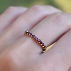 a woman's hand wearing a gold ring with red and white stones on it