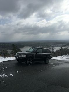 a black suv parked on top of a snow covered hill