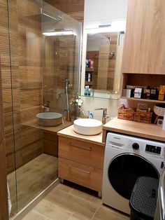 a washer and dryer sitting in a bathroom next to a shower stall with wood paneling on the walls