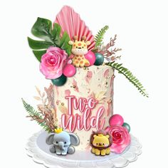 there is a cake decorated with flowers and animals on the top it says two wild