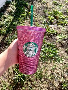 a hand holding a pink starbucks cup with a green straw