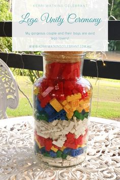 a glass jar filled with legos sitting on top of a white table next to a window