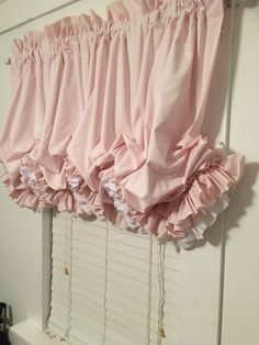 pink ruffled curtains hanging on the side of a window