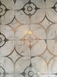 an intricately designed marble floor with gold and silver accents on the top part of it