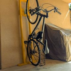 a bicycle is parked next to a wall with a bike cover on it's back