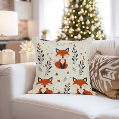 a christmas tree is in the background behind a white couch with pillows on it and a red fox print pillow case