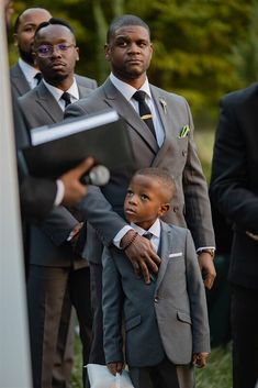 a man in a suit and tie holding a small boy