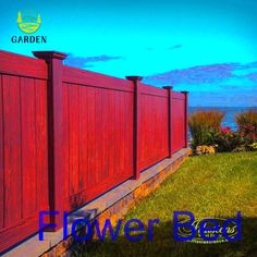 a red wooden fence in front of the ocean with blue sky and clouds behind it