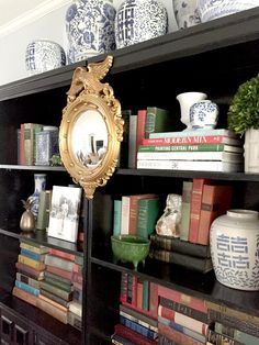 a bookshelf filled with lots of books and vases on top of it