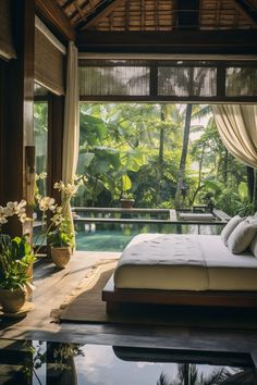 a large bed sitting next to a pool in a lush green forest covered resort room