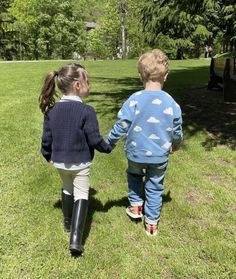 two children walking in the grass holding hands