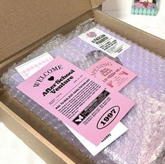 an open box with some pink stickers on it and other items in the package