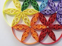 four different colored paper flowers on a white surface