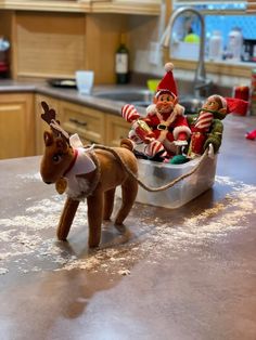 two elfs are riding in a sleigh on the kitchen counter with their reindeer