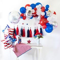 an american themed party with red, white and blue balloons on the wall next to a table