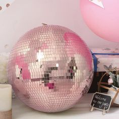 a disco ball sitting on top of a table next to a candle and some balloons