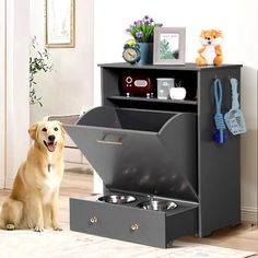 a dog sitting on the floor next to a cabinet with its door open and it's water bowl in front of it