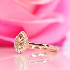 a yellow diamond ring sitting on top of a pink rose