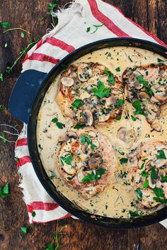 a skillet filled with mushrooms and sauce on top of a red and white towel