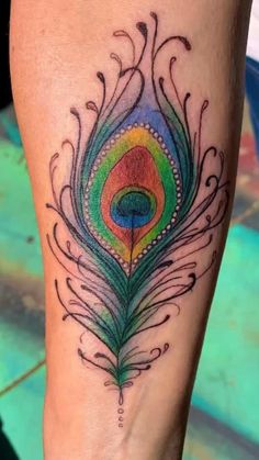 a colorful peacock feather tattoo on the leg