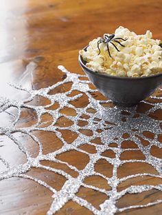 a bowl filled with popcorn sitting on top of a table next to a spider web