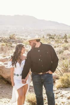 a man and woman holding hands in the desert