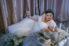 a woman is laying on the floor in a dress and holding a wine glass with her right hand