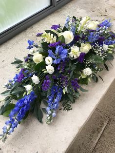 blue and white flowers are laying on the ground next to an open window sill