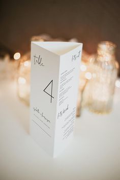 a white box with a black triangle on it sitting on a table next to candles