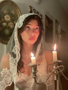 a woman wearing a veil and holding a candelabra with two lit candles