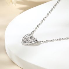 The "Pure Love" heart-shaped sterling silver necklace is a timeless token of affection, designed to captivate with its simplicity and elegance. The heart is crafted with precision, adorned with a sparkling array of round-cut and tapered baguette-cut stones. The stones catch the light, dancing and shimmering. It glimmers with a soft sheen, adding a touch of elegance to any ensemble. It is a symbol of pure, unwavering affection, perfect for any occasion that calls for a heartfelt expression of sen Valentine's Day Heart Necklace With Clavicle Chain, Elegant Silver Heart Necklace With Heart Beads, Heart-shaped Diamond Necklaces For Mother's Day, Sterling Silver Heart-shaped Necklace With Heart Beads, Diamond Heart Necklaces For Mother's Day, Sterling Silver Heart Cut Necklace With Heart Beads, Elegant Heart Beads Round Pendant Necklace, Elegant Heart Beads Necklace With Round Pendant, Elegant Necklace With Heart Beads And Round Pendant