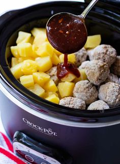 a slow cooker filled with meatballs, pineapples and ketchup