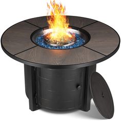 an outdoor fire pit with a circular table top and blue gravel around the bottom, on wheels