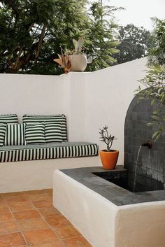 a couch sitting on top of a tiled floor next to a fire place in a garden