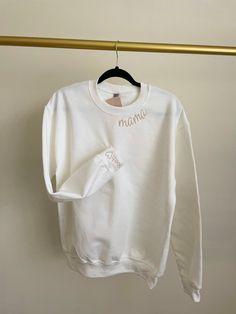 This super soft, comfy Sweatshirt is perfect for mama! It is the perfect mom fit for any day.  The word "mama" is embroidered in lilac color thread on a beige sweatshirt.   Personalized it by choosing thread color for "mama", sweatshirt  color and you can add your kid's initial to add a personal touch!  Are you looking for an item that is not listed? Please send me a message, I'd be happy to help create something special for you! Returns: All items are made-to-order. Because of the nature of these items, unless they arrive damage or defective I can't accept returns. I gladly accept cancellations within 4 hours of purchased you have only 4 hours to make any  changes or cancelations. refer back to our policy if you have any questions reach out, happy to answer all your questions or concerns. Custom Embroidered White Tops For Mother's Day, White Tops With Letter Embroidery For Mother's Day, Personalized White Cotton Top, Personalized White Sweatshirt For Gift, Everyday White Tops With Letter Embroidery, White Sweatshirt With Letter Embroidery As Gift, White Everyday Sweatshirt With Letter Embroidery, White Sweatshirt With Letter Embroidery For Everyday, White Sweatshirt With Letter Embroidery