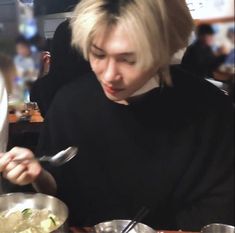 a woman sitting at a table in front of a bowl of food with a spoon