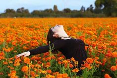 a woman laying on her back in a field of orange flowers with her arms stretched out