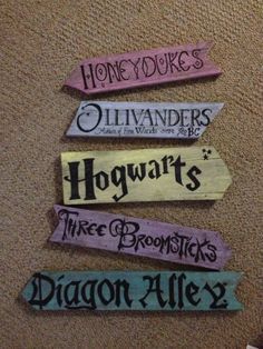 four wooden signs that say hogwarts, three broomsticks, and three dragon alleys