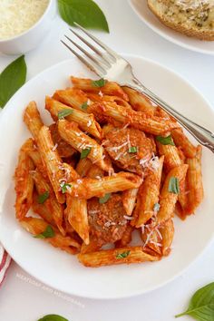 pasta with meat sauce and parmesan cheese on a white plate next to bread