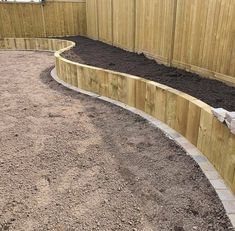 a wooden fence surrounding a garden area with dirt on the ground and rocks in the middle