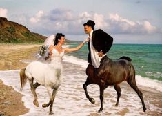 a bride and groom are riding horses on the beach