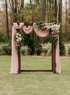 an outdoor wedding arch with pink drapes and flowers