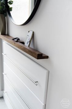 a white dresser with a mirror and cell phone on it