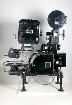 an old fashioned camera sitting on top of a tripod in front of a white background