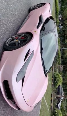 a pink sports car parked on the side of a road