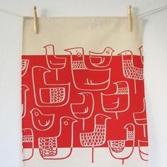 a red and white tea towel hanging on a clothes line with birds in the background