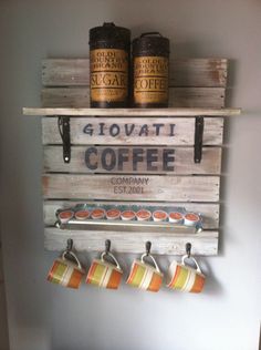 a wooden sign with coffee cups hanging from it's sides and two mugs on the shelf