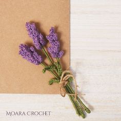 a bunch of lavender flowers sitting on top of a piece of brown paper next to a string